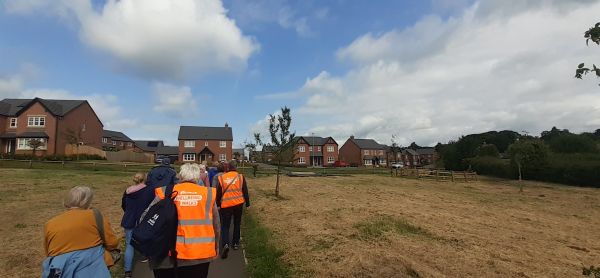 A group of people walking along a paved path in a greenspace