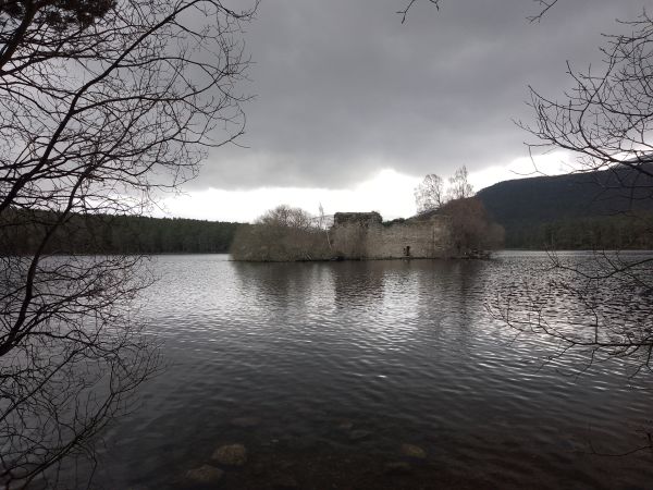 View of castle ruin on loch with grey sky