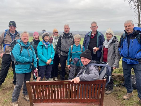 A group of Ramblers by a bench on a grey winter's day