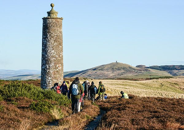Walkers at the McKenzie Meridien monument with Kinpurney Hill in the distance