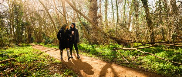 Two women walking along a woodland path