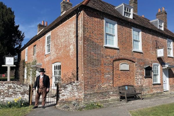 A man in top hat and suit standing outside of a building