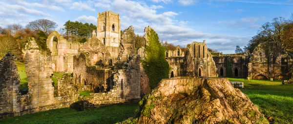 Ripon, Yorkshire, UK. The ruins of Fountains Abbey on a fine autumn morning as viewed from across the river Skell near Ripon, Yorkshire, UK.