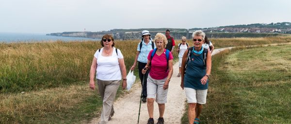 A group of people walking along a path that curves along the coast