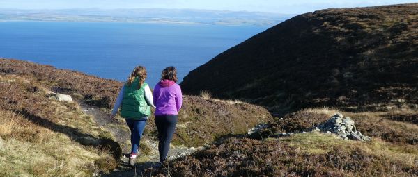 Two people walking alone a coastal path