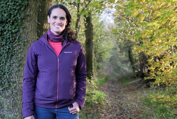 A woman standing in front of a path in the woods