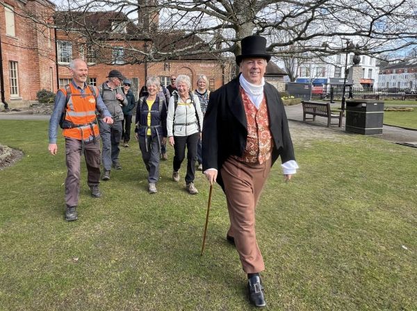 Man in Regency costume leading a group of walkers