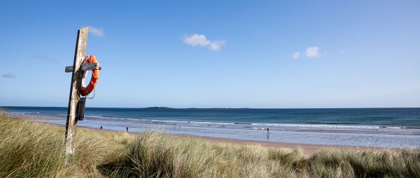 A life-buoy on its stand, beside a wide empty beach