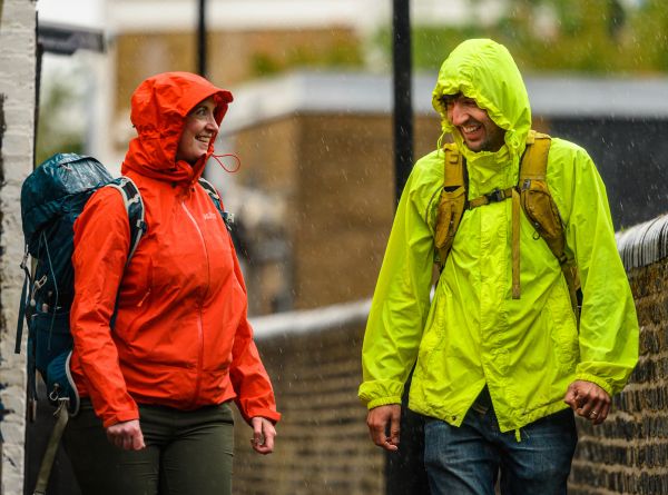 A woman and a man laughing as they walk in the rain