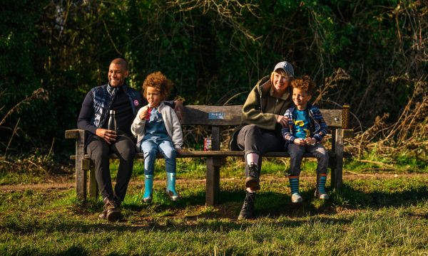 A family sitting on two park benches, having a snack and looking out at the view