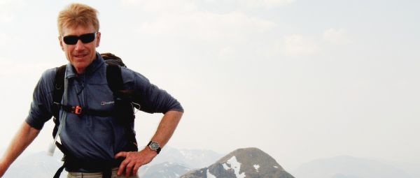 Colin on a Skye mountain in 2002, with snowy hills beyond