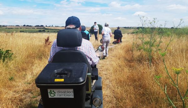 Mobility scooters and people using a path running through grasses