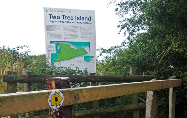 Sign for Two Tree Island beside a wooden fence