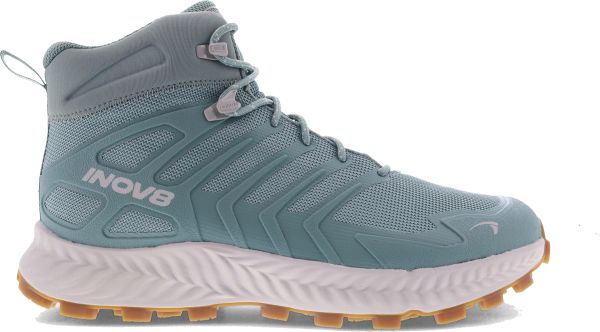 A light green mid-cut trail shoe with a breathable mesh upper, reinforced side panels, and ‘Inov‑8’ branding, featuring a cushioned white midsole and a tan rubber outsole with deep lugs for off‑road grip.