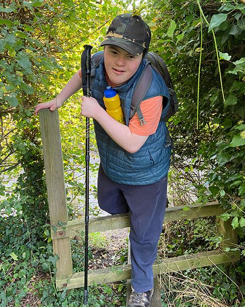 A young man stepping over a stile