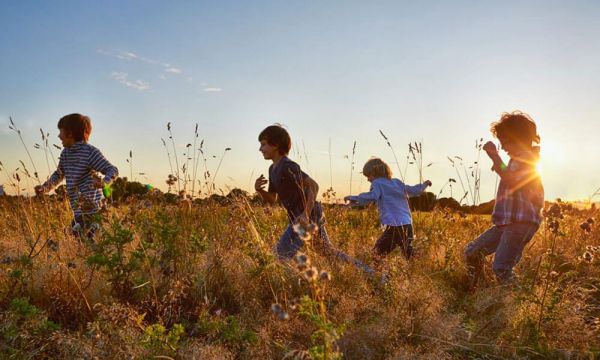 Four children running through long grass