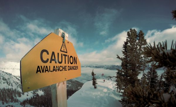 A sign at the top of a mountain which says "Caution Avalanche Danger"