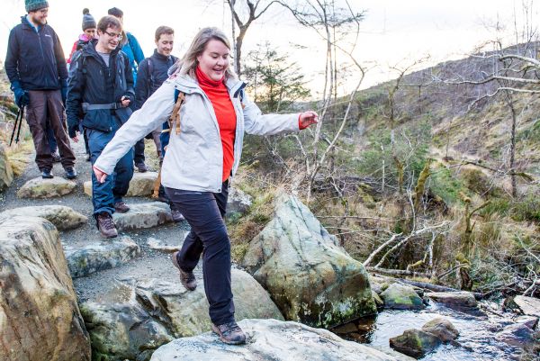 A group of Ramblers crossing a river using stepping stones