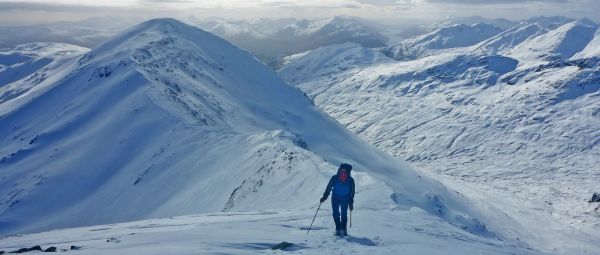 A person walking alone up a steep snowy hill