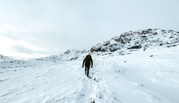 man walking in snow covered hill