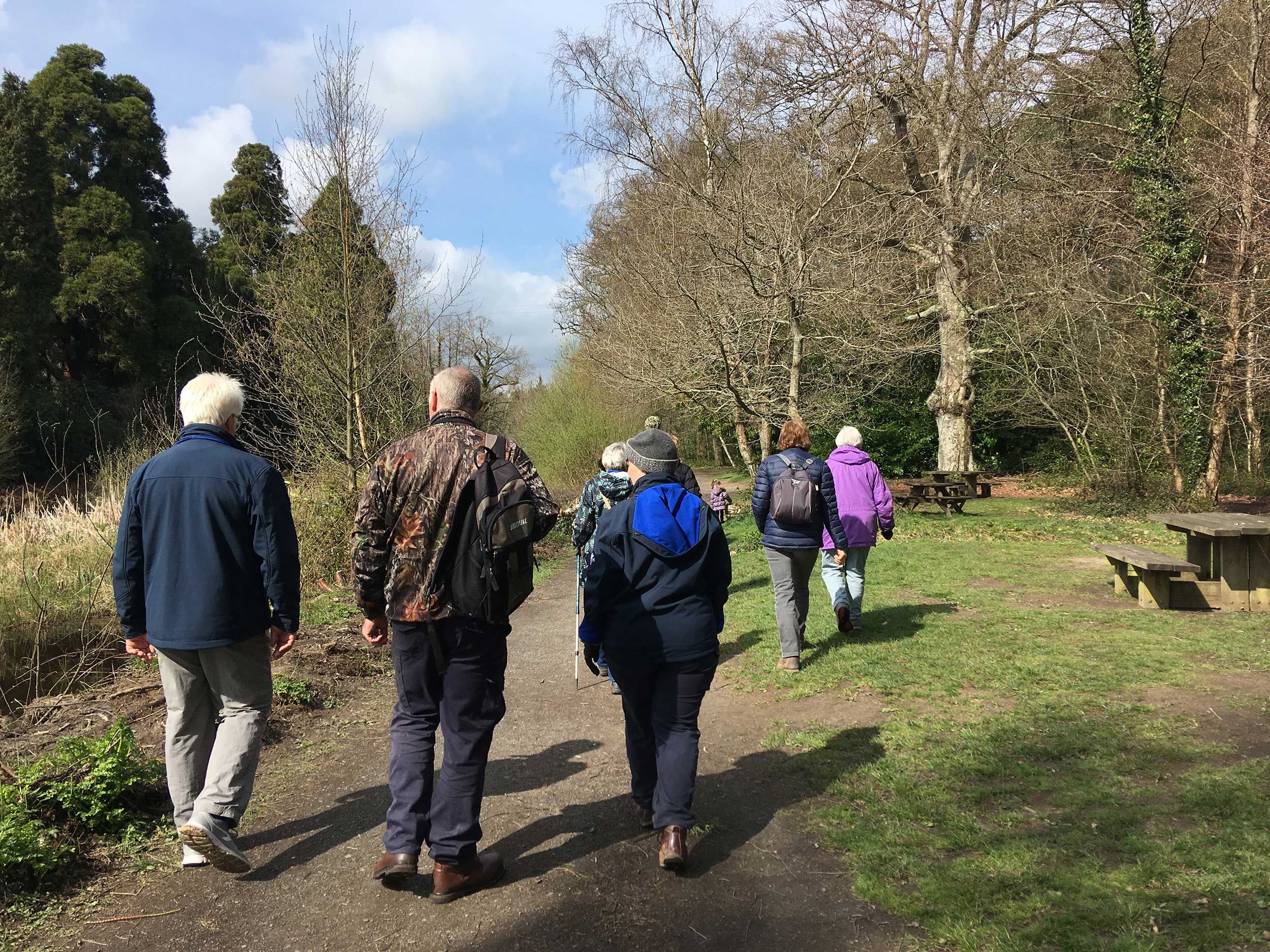 walkers on a park path near a picnic bench