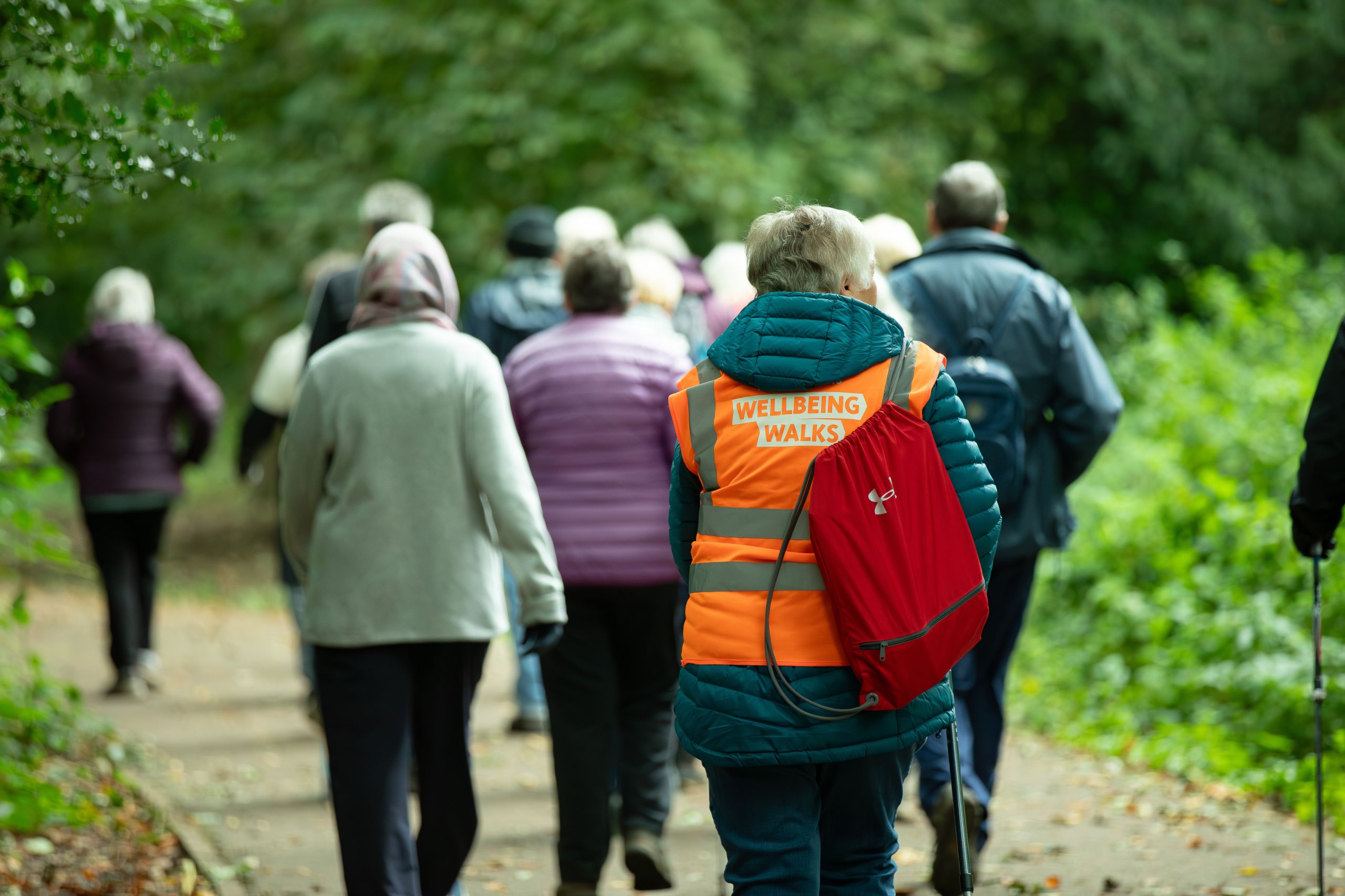 A walk leader and walkers walking along a path